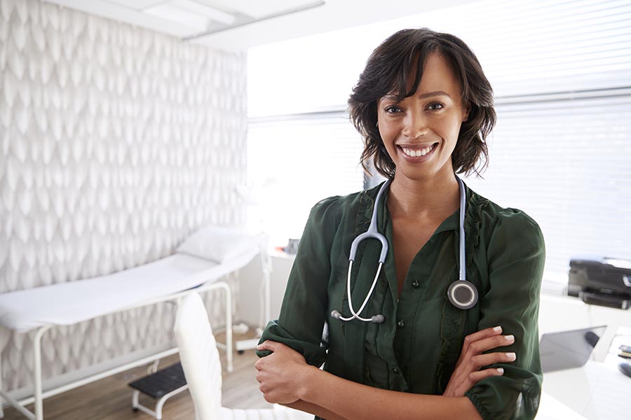 Life and Health Insurance - Doctor Wearing a Stethoscope in an Exam Room, Smiling